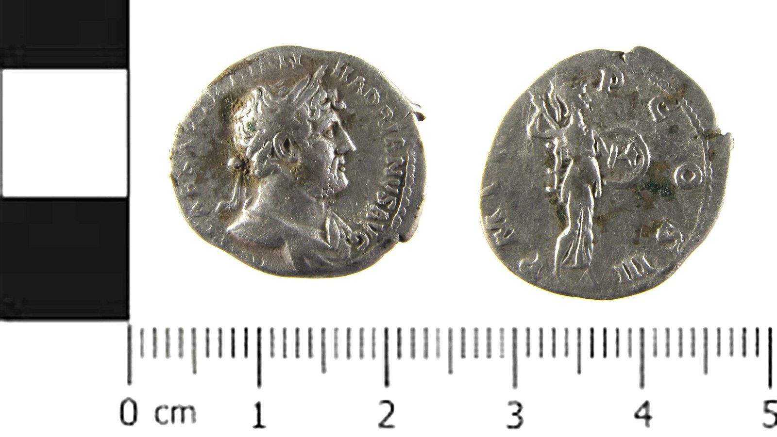 Een oude zilveren Romeinse munt met het hoofd van een keizer aan de ene kant en een staande figuur aan de andere kant.