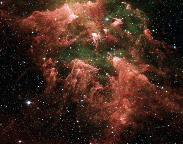 Roze en groene gaswolken met pilaren van gas en stof, omringd door veel kleine sterren in de ruimte.