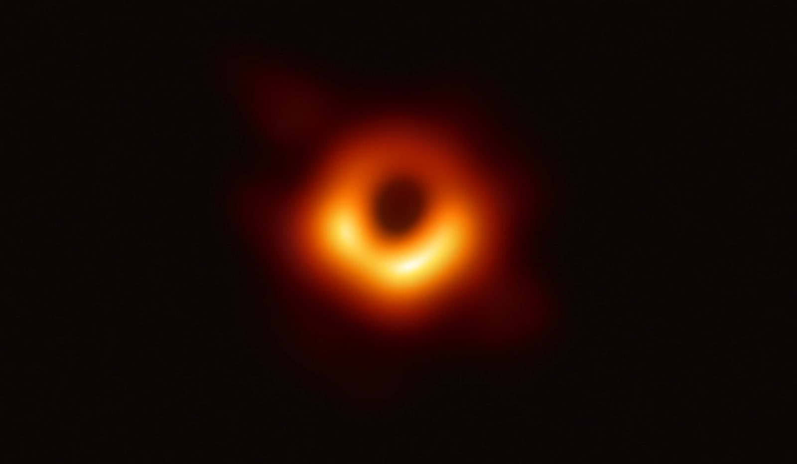 Een oranje, gloeiende ring van licht met een donker gat in het midden: het zwarte gat in sterrenstelsel M87.